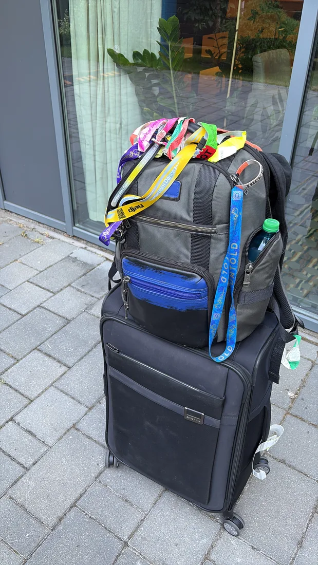 Koffer en rugzak klaar voor vertrek, met een verzameling festivalbandjes en lanyards erbovenop